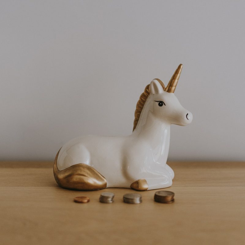 white and gold ceramic unicorn figurine near coins